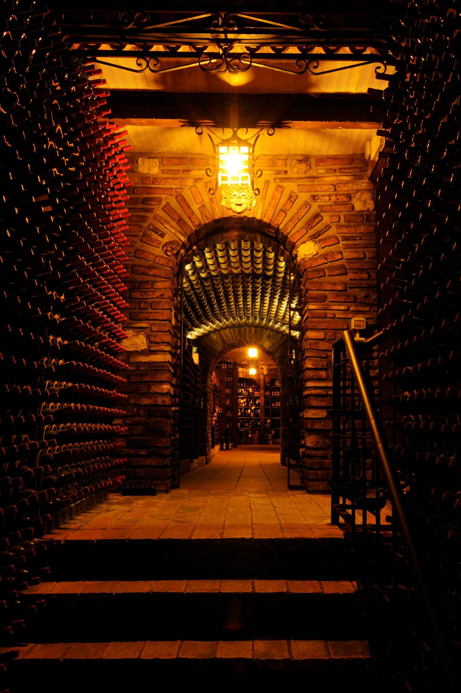 Arco della cantina storica di notte, con lanterna e scale